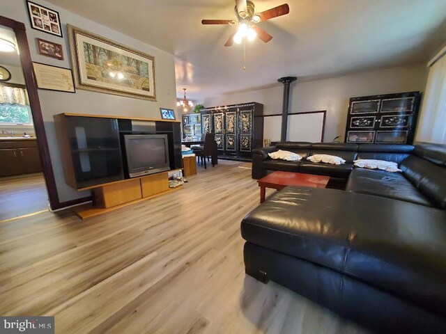 living room with ceiling fan with notable chandelier, sink, and wood-type flooring