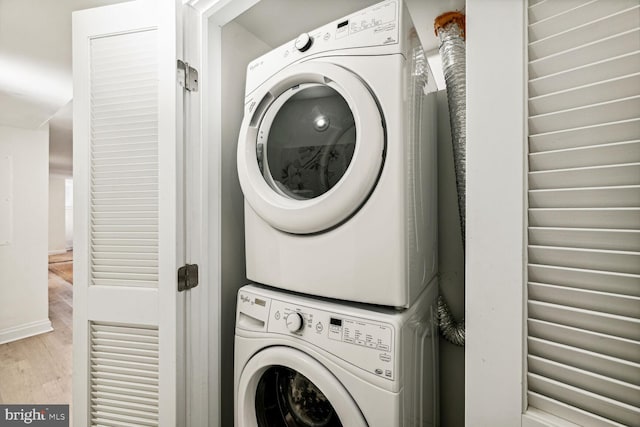 laundry room with stacked washer / dryer and light hardwood / wood-style floors