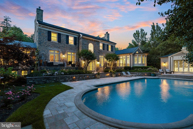 pool at dusk with a patio area