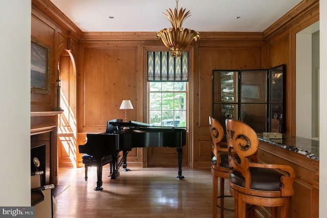 misc room with a notable chandelier, wood walls, and wood-type flooring