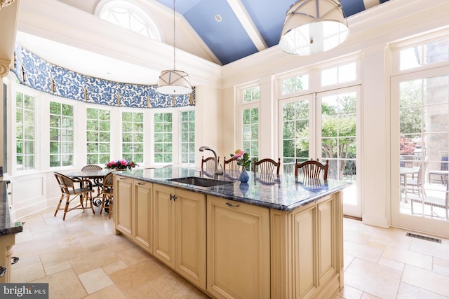 kitchen featuring pendant lighting, plenty of natural light, a kitchen island with sink, and sink