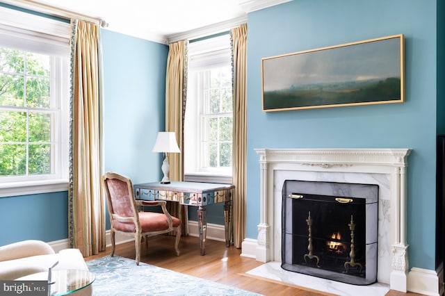 sitting room featuring plenty of natural light, crown molding, a premium fireplace, and hardwood / wood-style flooring