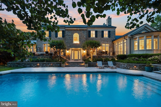 pool at dusk with a patio area