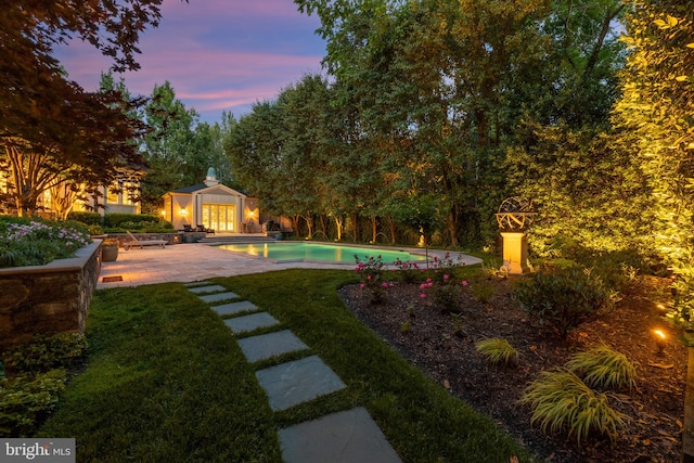 yard at dusk with an outdoor structure and a patio area