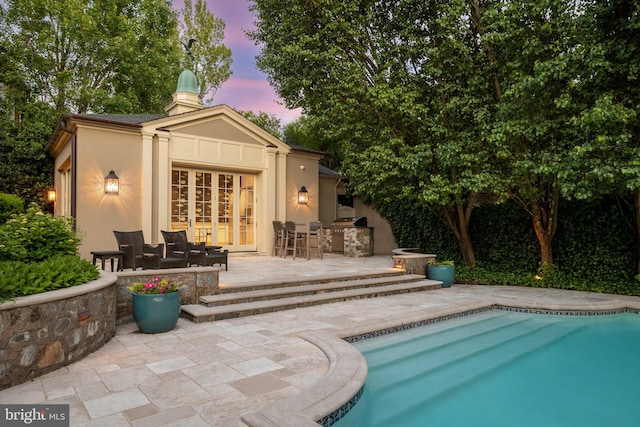 back house at dusk featuring a patio