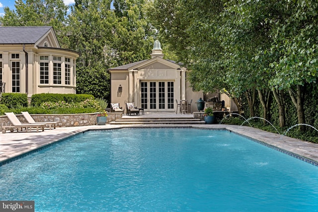 view of swimming pool featuring french doors, a patio, an outdoor structure, and pool water feature