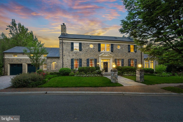 colonial inspired home featuring a garage and a lawn