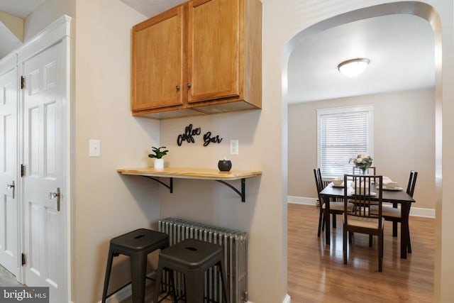 kitchen featuring light hardwood / wood-style flooring, a breakfast bar, and radiator