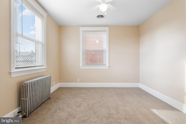 empty room with light carpet, ceiling fan, and radiator