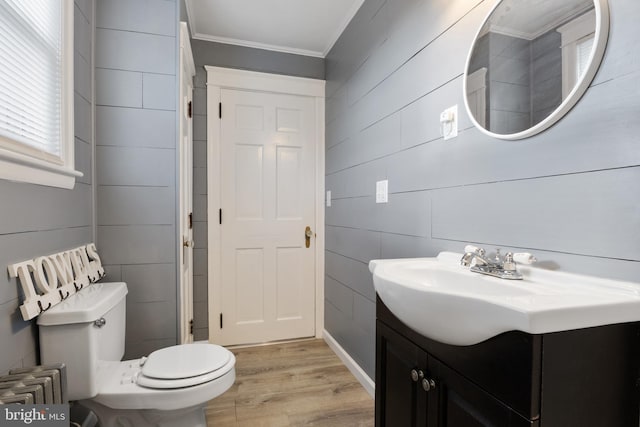 bathroom featuring radiator heating unit, vanity, hardwood / wood-style flooring, crown molding, and toilet