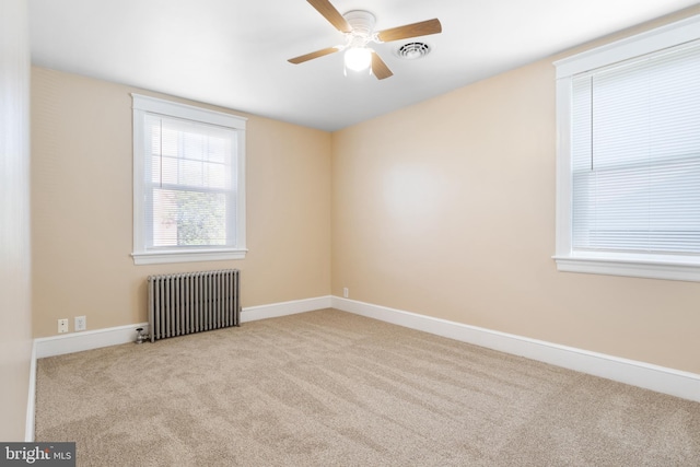 carpeted empty room with ceiling fan and radiator heating unit