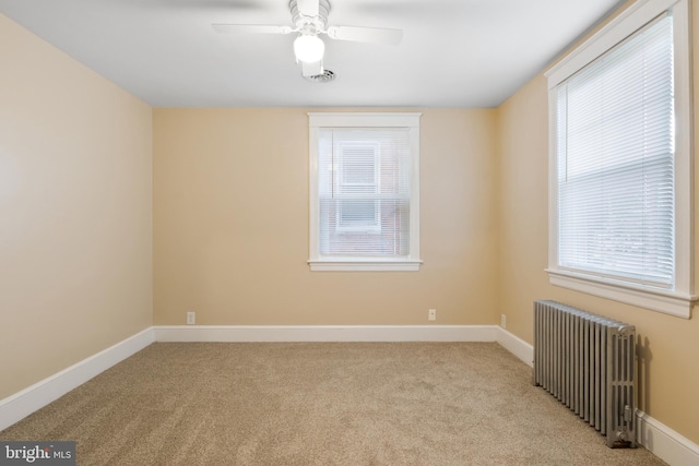 empty room with ceiling fan, light colored carpet, a wealth of natural light, and radiator