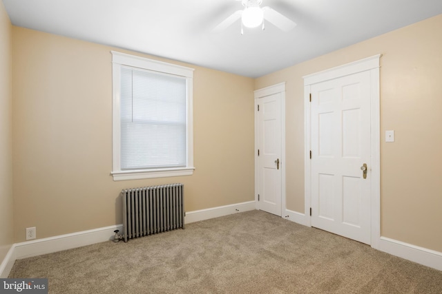 empty room with ceiling fan, radiator, and light colored carpet