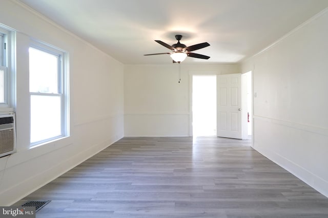 empty room with ceiling fan, plenty of natural light, ornamental molding, and hardwood / wood-style flooring