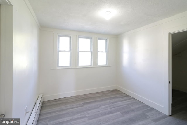 spare room featuring a baseboard heating unit, a textured ceiling, and light hardwood / wood-style flooring