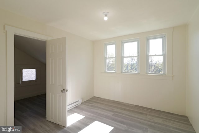 spare room with hardwood / wood-style floors and a baseboard heating unit