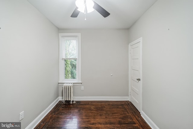 unfurnished room with ceiling fan, radiator, and dark hardwood / wood-style flooring