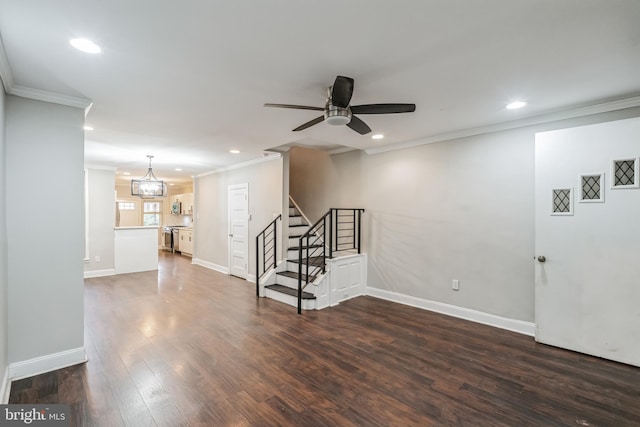 unfurnished living room featuring ceiling fan with notable chandelier, dark hardwood / wood-style floors, and ornamental molding