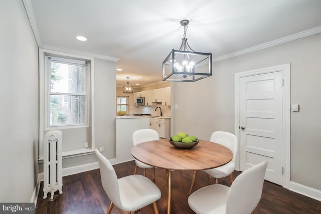 dining space featuring an inviting chandelier, dark hardwood / wood-style floors, sink, and crown molding