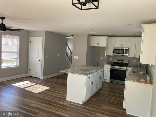 kitchen featuring stainless steel appliances, white cabinetry, dark hardwood / wood-style flooring, and a center island