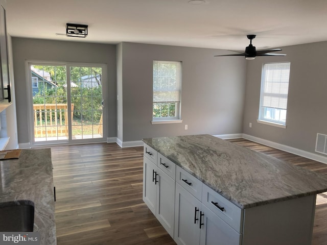 kitchen featuring ceiling fan, white cabinets, light stone countertops, and plenty of natural light