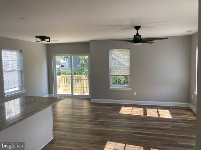 unfurnished dining area featuring ceiling fan, a wealth of natural light, and dark hardwood / wood-style floors