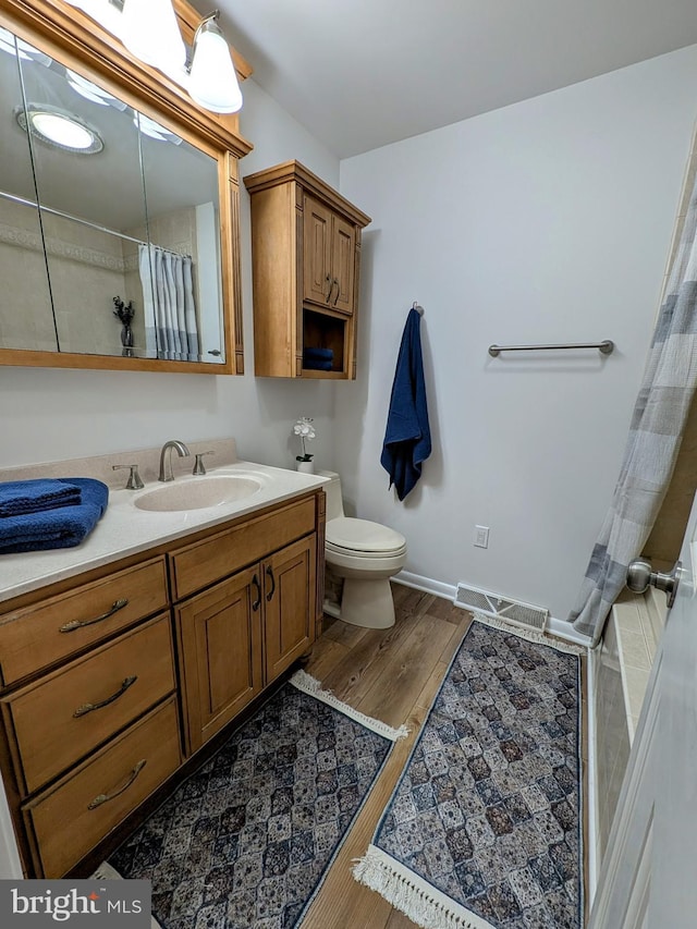 bathroom featuring hardwood / wood-style floors, vanity, a shower with shower curtain, and toilet