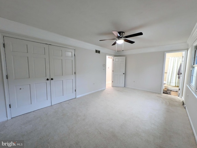 unfurnished bedroom with ceiling fan, light colored carpet, ornamental molding, and a closet