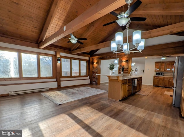 kitchen featuring a baseboard heating unit, sink, a notable chandelier, stainless steel refrigerator, and an island with sink