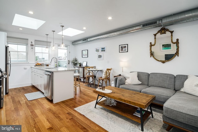 living room with a skylight, sink, and light wood-type flooring