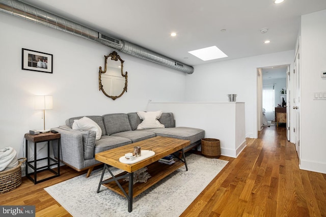 living room with a skylight and hardwood / wood-style flooring