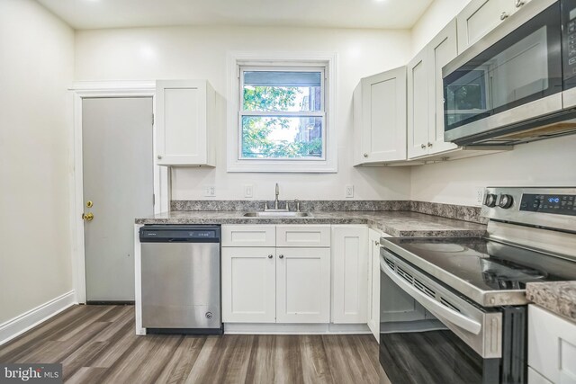 kitchen featuring appliances with stainless steel finishes, dark hardwood / wood-style floors, and white cabinetry