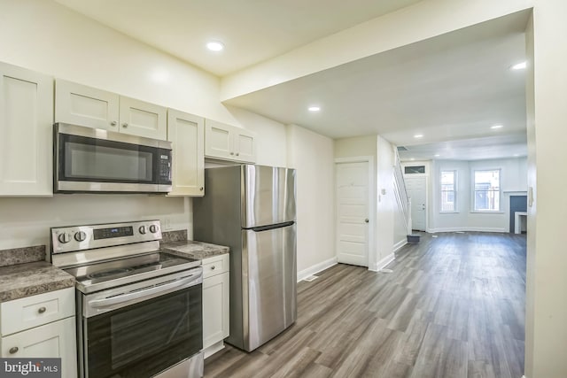 kitchen with appliances with stainless steel finishes, light hardwood / wood-style floors, and white cabinets