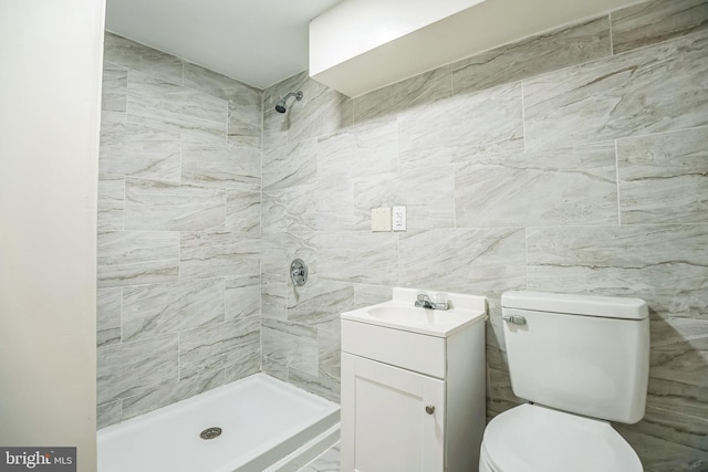 bathroom with tile walls, vanity, tiled shower, and toilet