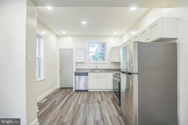 kitchen featuring sink, appliances with stainless steel finishes, white cabinets, and light hardwood / wood-style floors