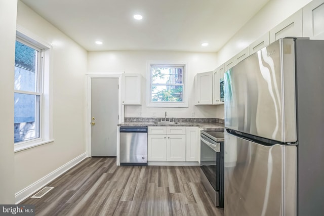 kitchen featuring sink, appliances with stainless steel finishes, dark hardwood / wood-style floors, and white cabinetry