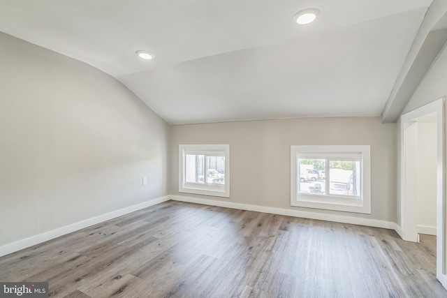 unfurnished room featuring lofted ceiling, light hardwood / wood-style floors, and plenty of natural light