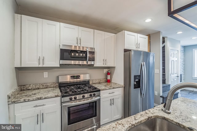 kitchen featuring light stone countertops, sink, appliances with stainless steel finishes, and white cabinetry