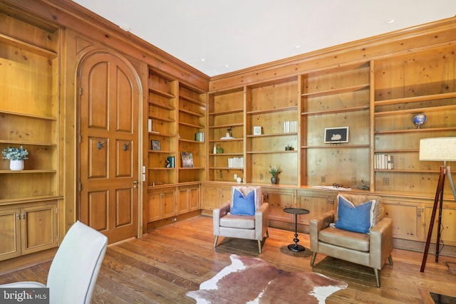 living area featuring ornamental molding, built in features, and wood-type flooring