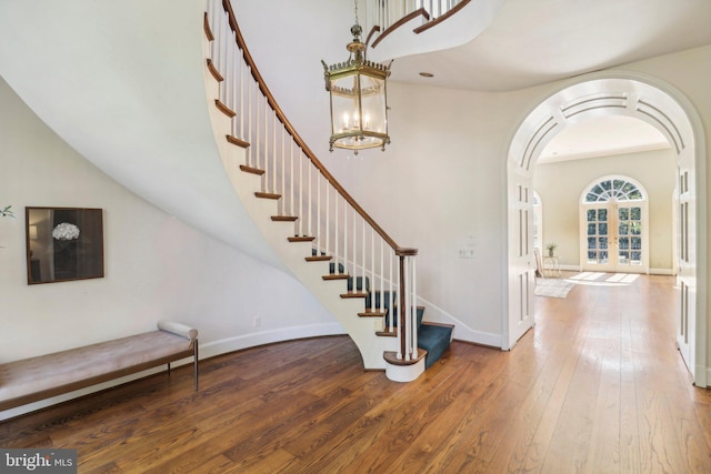 foyer featuring french doors, hardwood / wood-style flooring, and an inviting chandelier