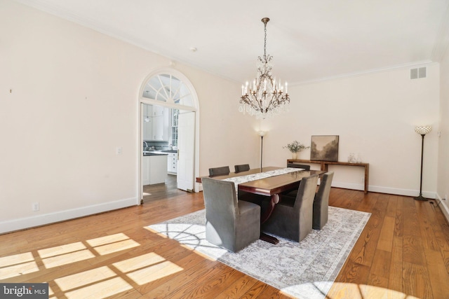 dining space with a notable chandelier, light hardwood / wood-style floors, and ornamental molding