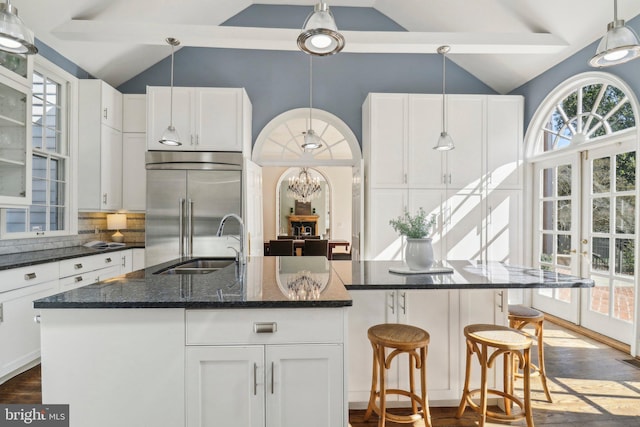 kitchen featuring built in refrigerator, a kitchen island with sink, and white cabinets