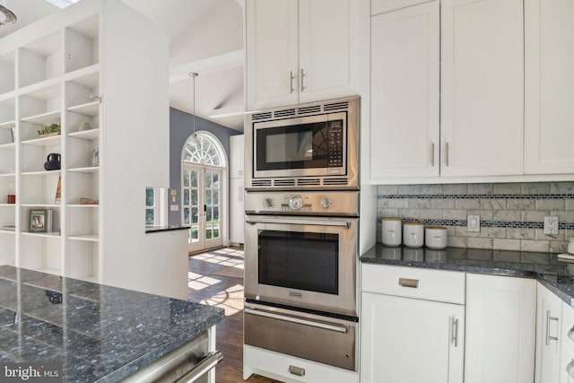 kitchen with tasteful backsplash, white cabinets, dark stone countertops, dark wood-type flooring, and appliances with stainless steel finishes