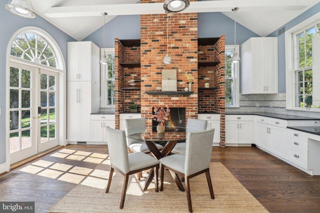 dining space with a brick fireplace, french doors, lofted ceiling with beams, and dark hardwood / wood-style flooring