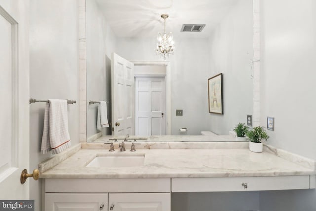 bathroom with a notable chandelier, vanity, and toilet