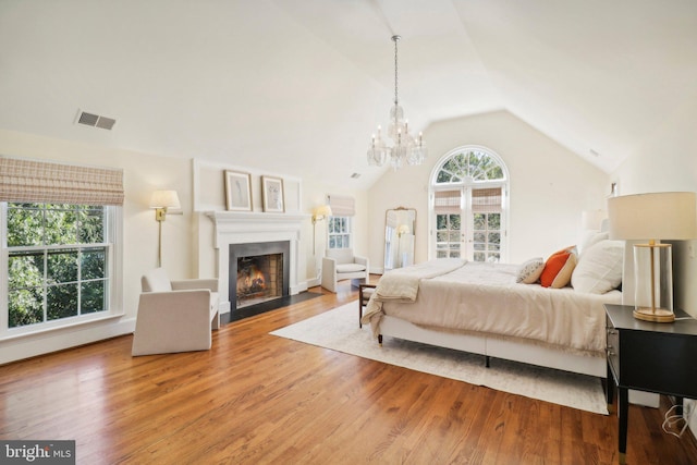 bedroom featuring hardwood / wood-style flooring, vaulted ceiling, and an inviting chandelier