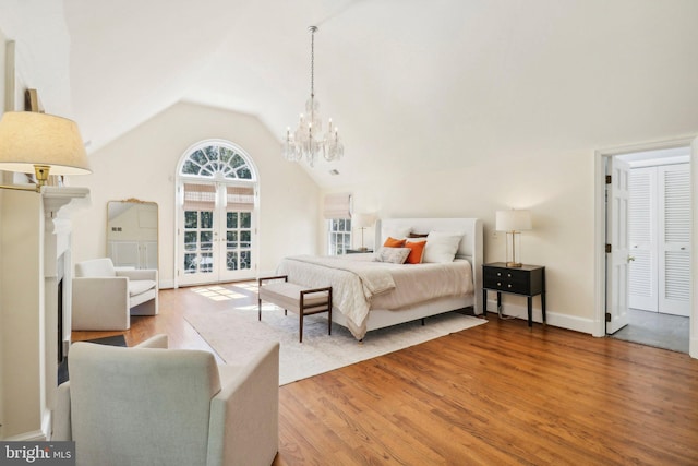 bedroom with wood-type flooring, french doors, vaulted ceiling, and a notable chandelier