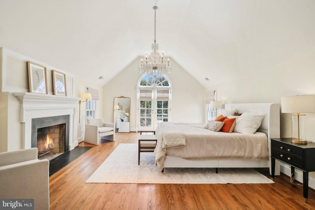 bedroom featuring an inviting chandelier, lofted ceiling, and hardwood / wood-style floors