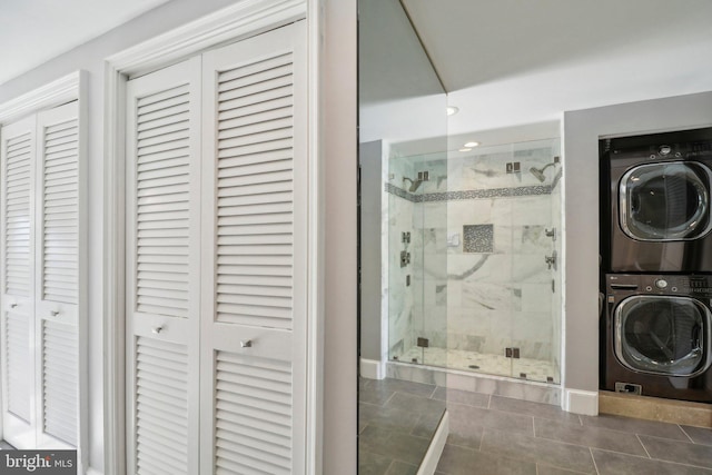 bathroom featuring a shower with shower door, stacked washer / drying machine, and tile patterned floors