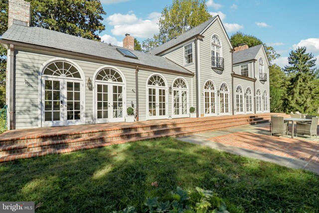 rear view of property featuring a patio, french doors, and a lawn